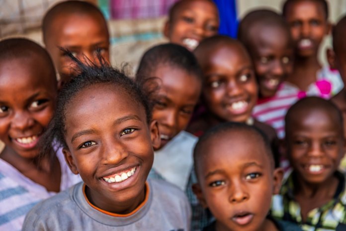 Children in a Ugandan classroom, smiling at the camera